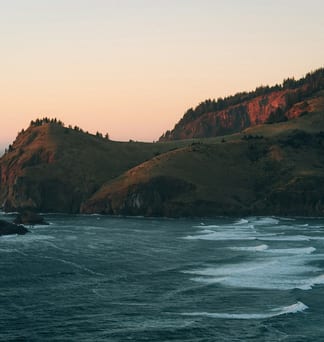 Rosy morning light on a green headland above the Oregon coast.